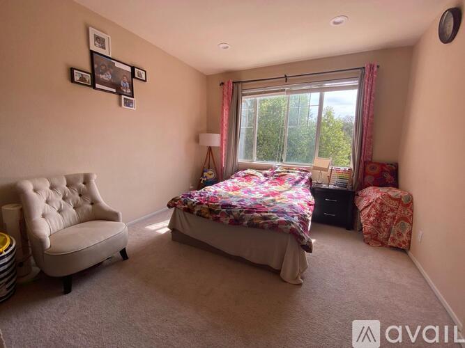 A bedroom with a large bed, a chair, and a window with curtains.
