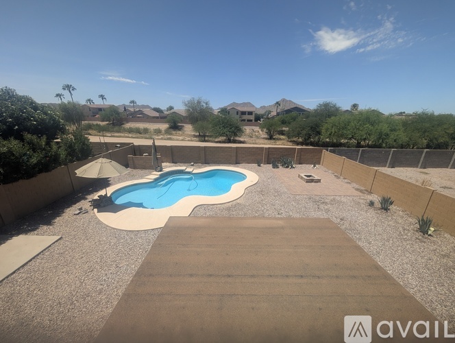 A pool surrounded by a concrete patio and a gravel area.