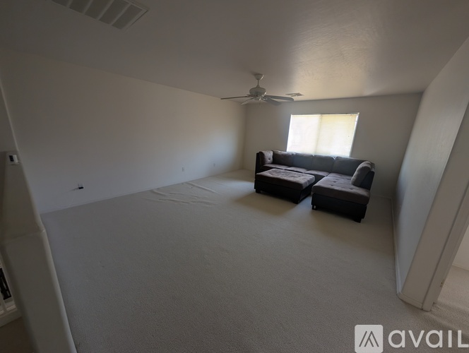 A living room with a couch and a fan.