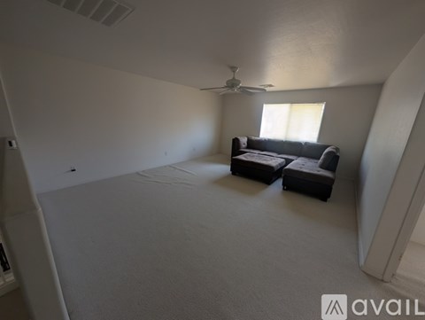 A living room with a couch and a fan.