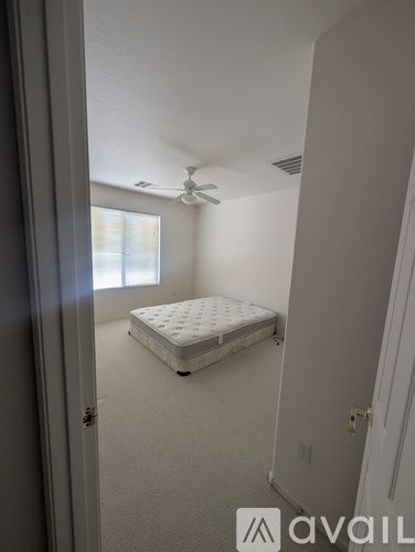A bed in a small bedroom with a fan on the ceiling.