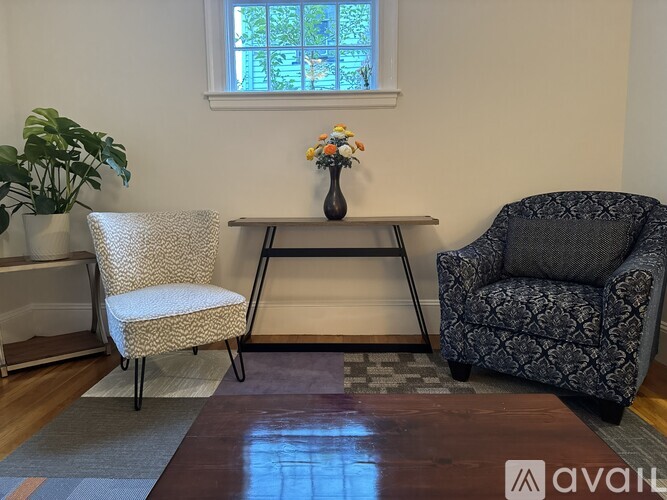 A living room with a grey armchair, a white chair, and a coffee table.