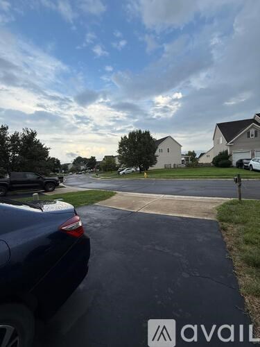 A car is parked on a driveway with a house in the background.
