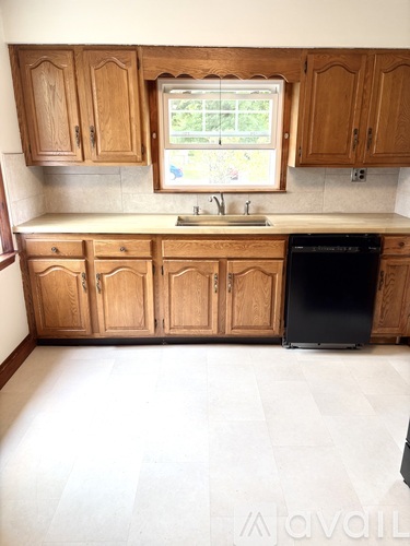 A kitchen with wooden cabinets and a black dishwasher.