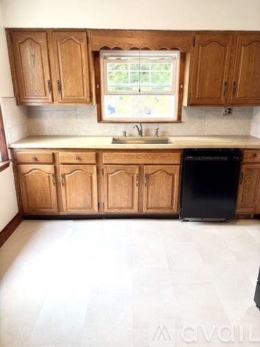 A kitchen with wooden cabinets and a black dishwasher.
