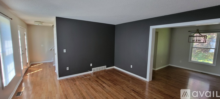 A room with wooden floors and a window on the left side.