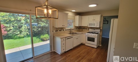 A kitchen with white cabinets and a wooden floor.