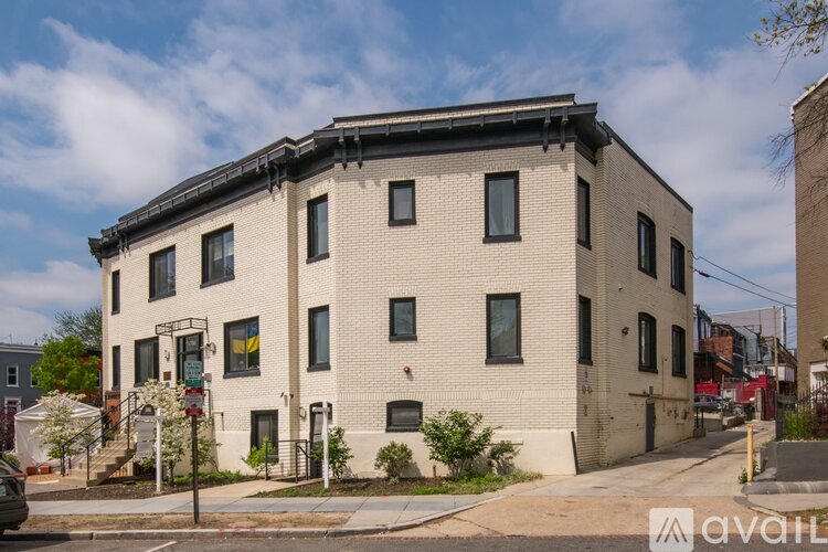 A beige brick building with a black roof and a sign that says "available" in front of it.
