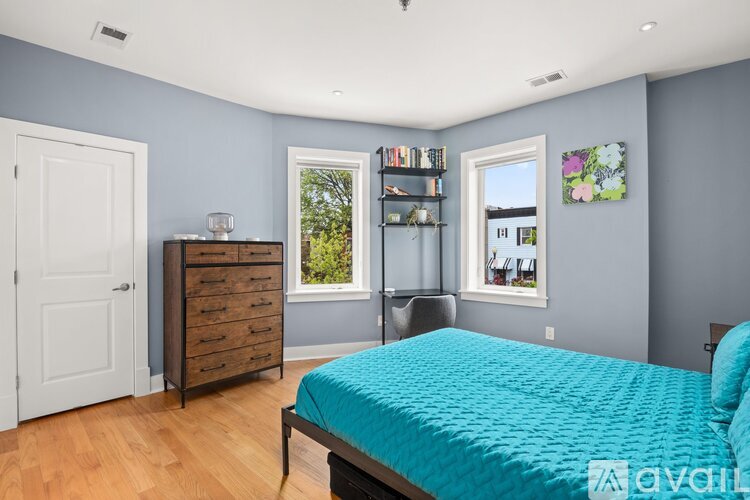 A bedroom with a blue bedspread and a wooden floor.