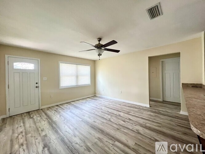 A room with a ceiling fan and wooden flooring.