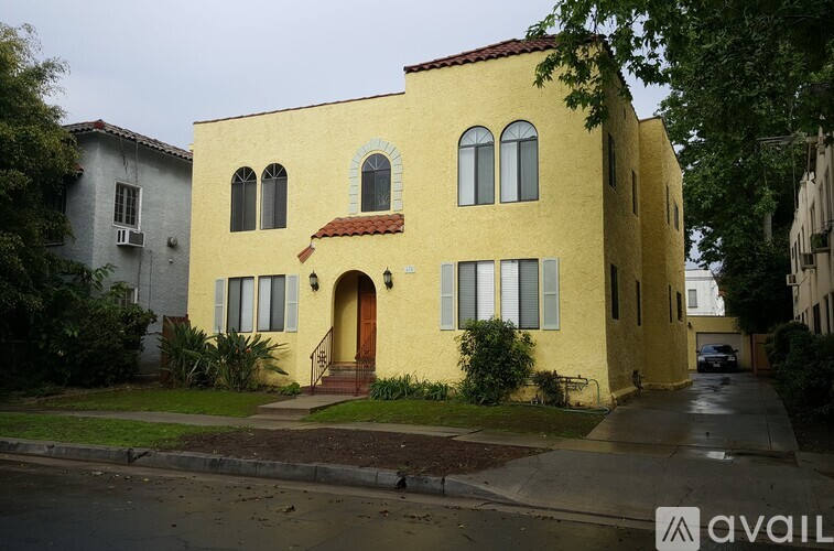 A yellow house with a red tile roof and a brown door.