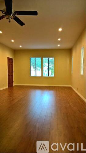 A room with a ceiling fan and wooden flooring.