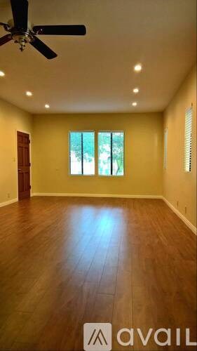 A room with a ceiling fan and wooden flooring.
