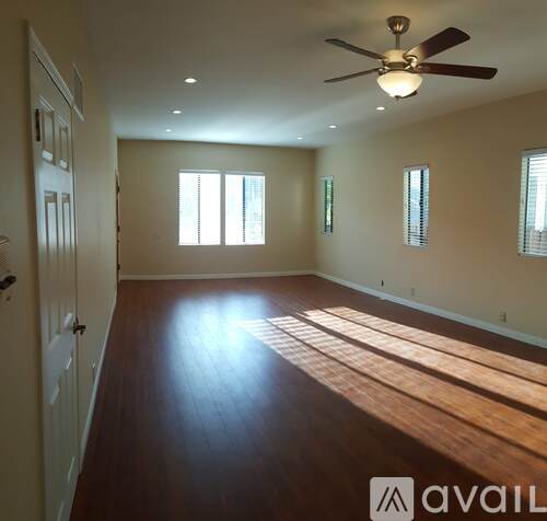 A spacious room with wooden floors and a ceiling fan.