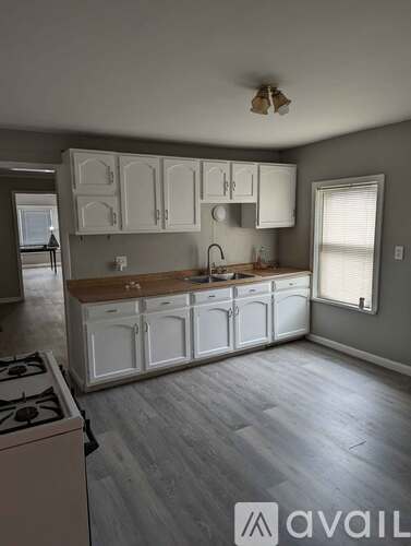 A kitchen with white cabinets and a wooden countertop.