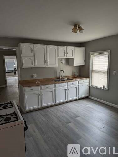 A kitchen with white cabinets and a wooden countertop.