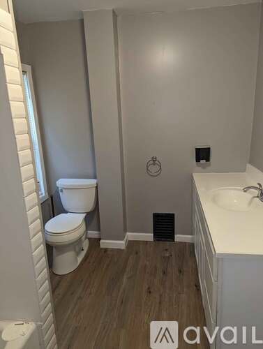 A bathroom with a toilet, sink, and a towel rack.