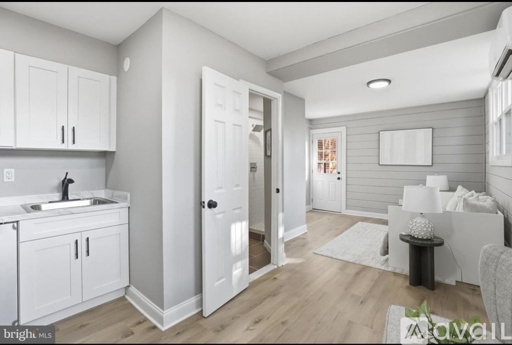 A modern kitchen with white cabinets and a wooden floor.