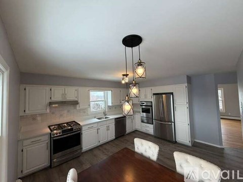 A modern kitchen with a wooden table and white chairs.