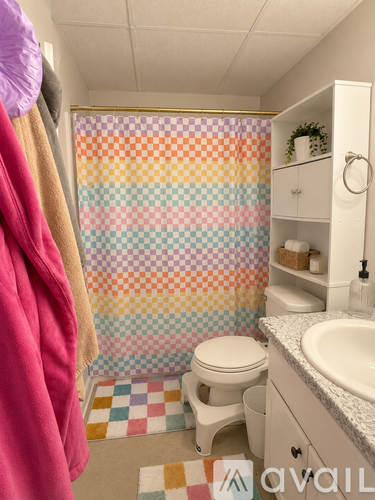 A bathroom with a checkered shower curtain and a towel hanging on the door.