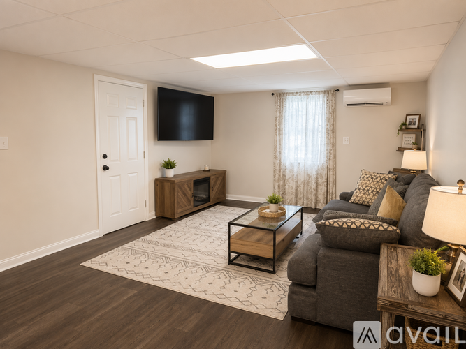 A living room with a grey couch, a coffee table, and a flat screen TV mounted on the wall.