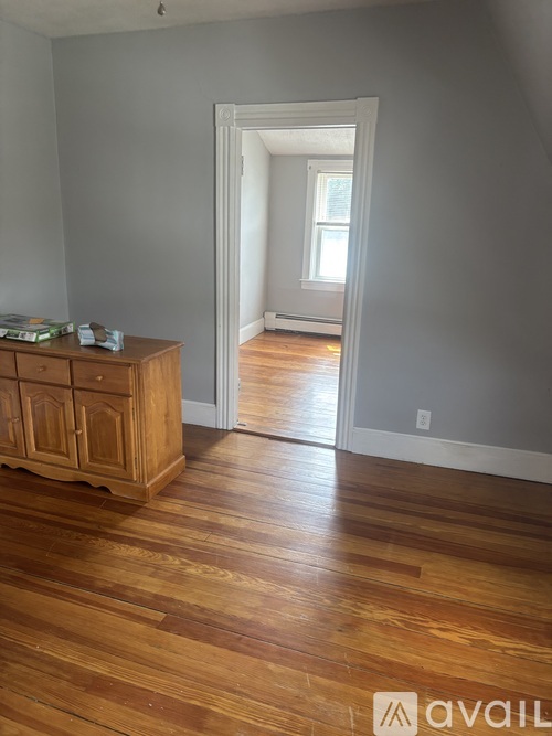 A room with wooden floors and a cabinet with books on top.