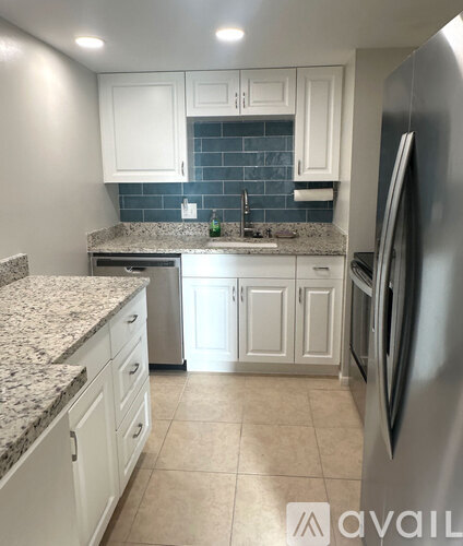 A kitchen with white cabinets and a granite countertop.