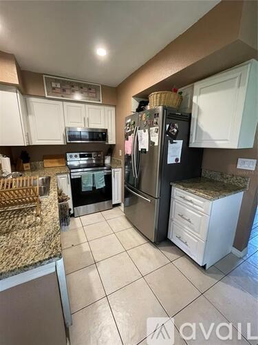 A kitchen with a granite counter top and a refrigerator.