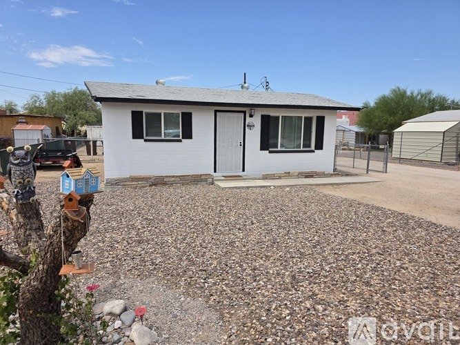 A small white house with a gravel driveway in front.
