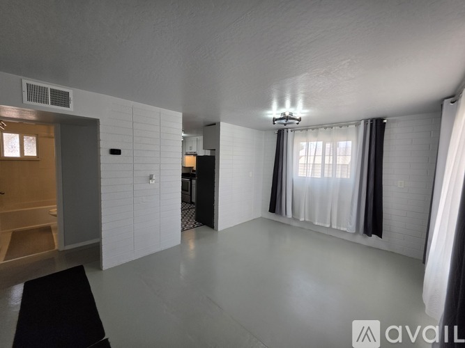 A spacious room with a large window and a chandelier.