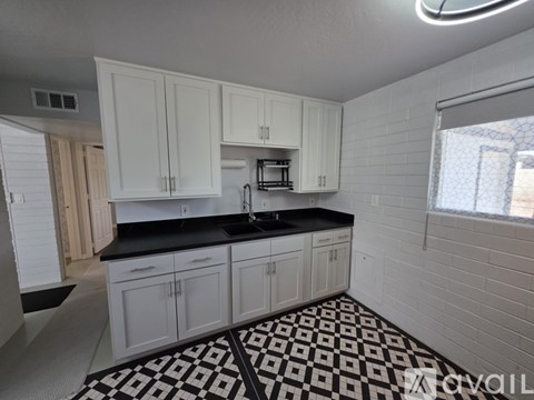 A kitchen with white cabinets and black countertops.