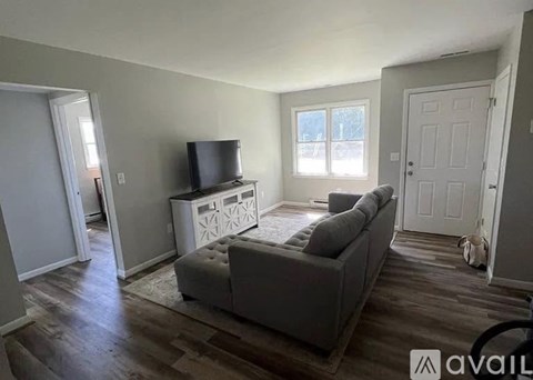A living room with a grey couch and a television on a white cabinet.