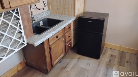 A kitchen with wooden cabinets and a black fridge.