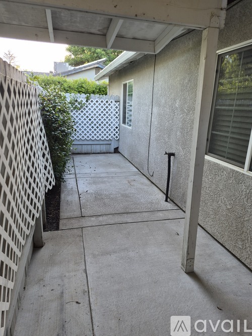A patio area with a white lattice fence and a concrete floor.
