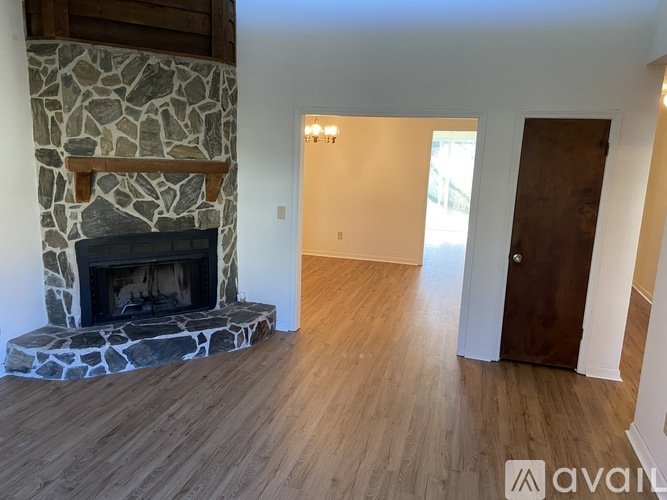A stone fireplace in a room with wooden floors and a door.