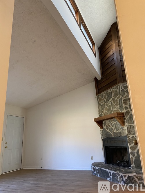 A room with a stone fireplace and wooden shelves.