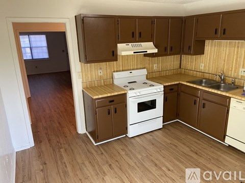 A kitchen with wooden cabinets and a white stove top oven.