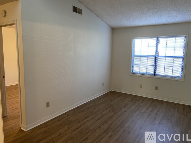 A room with wooden flooring and a window with blinds.