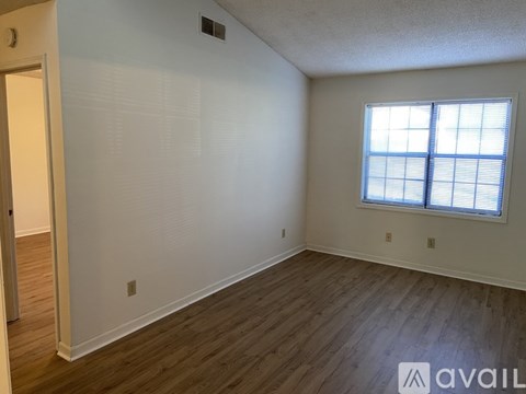 A room with wooden flooring and a window with blinds.