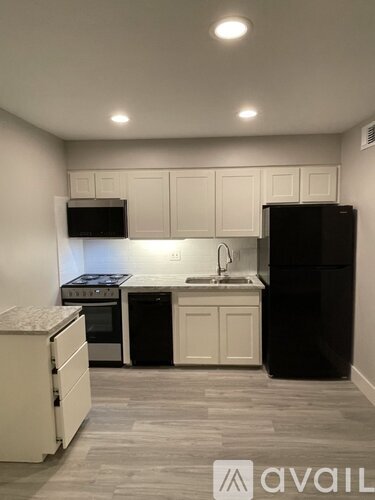 A kitchen with black appliances and white cabinets.