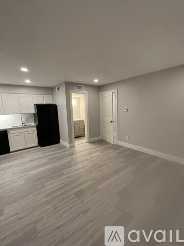 A kitchen with a black fridge and white cabinets.