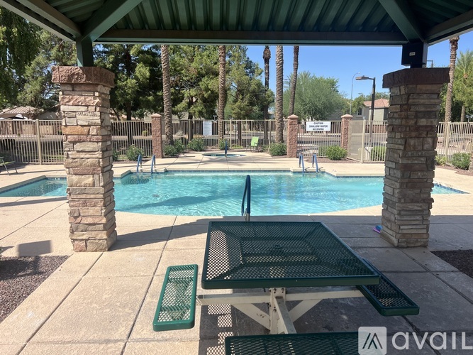 A pool area with a table and chairs under a roof.