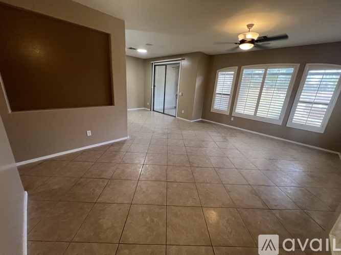 A spacious room with tiled flooring and a ceiling fan.