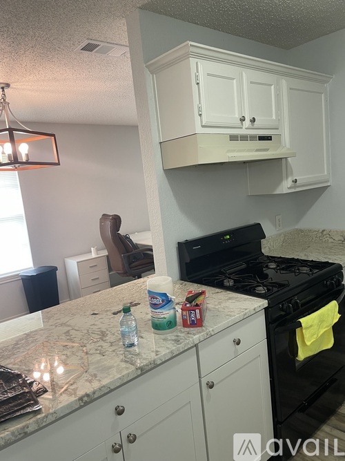 A kitchen with a black stove top oven and white cabinets.