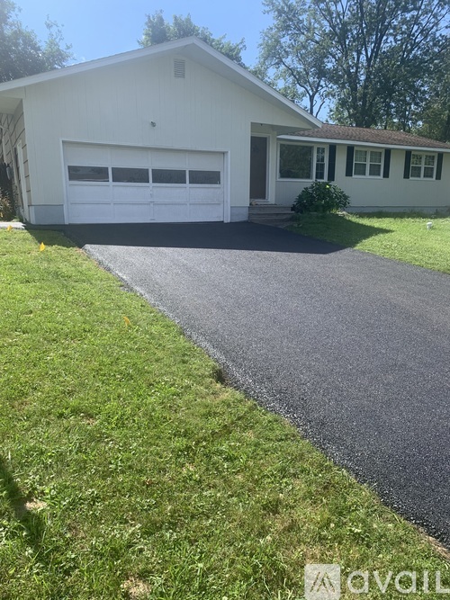 A white house with a grey garage door and a grey driveway.