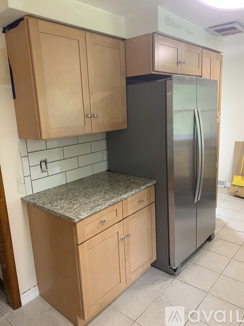 A kitchen with wooden cabinets and a black refrigerator.