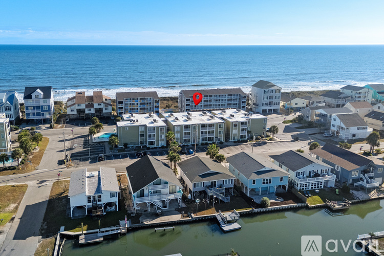 A bird's eye view of a coastal residential area with apartment buildings and boats docked in the marina.