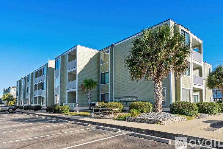A modern apartment building with a parking lot in front.