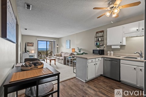A well-lit kitchen and living room with a dining table and chairs.