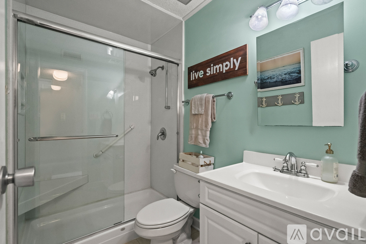 A bathroom with a glass shower stall and a toilet.